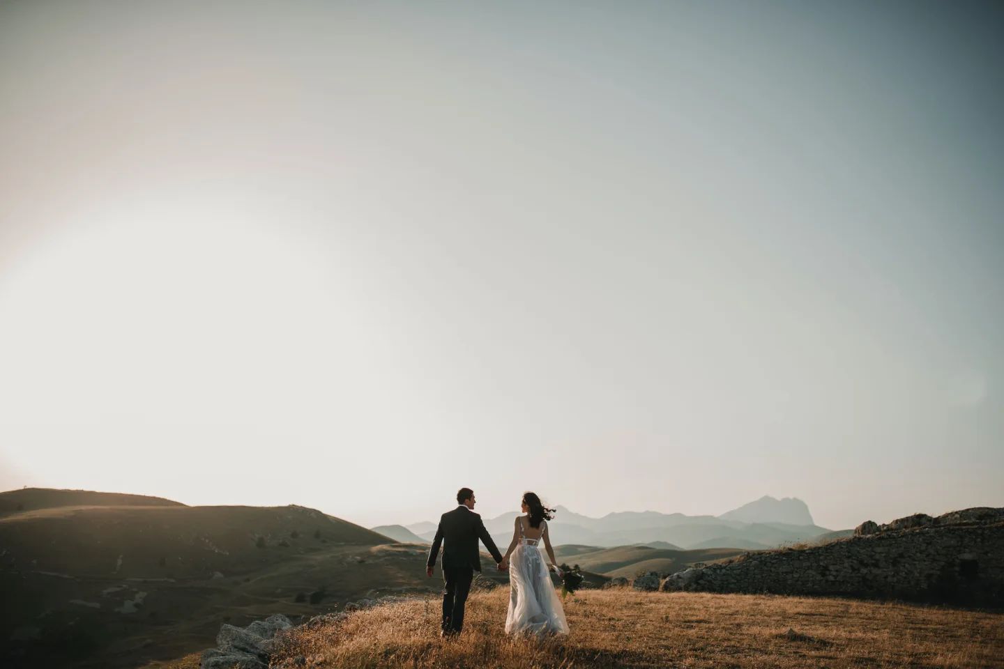 Wedding couple holding hands in a wide open landscape